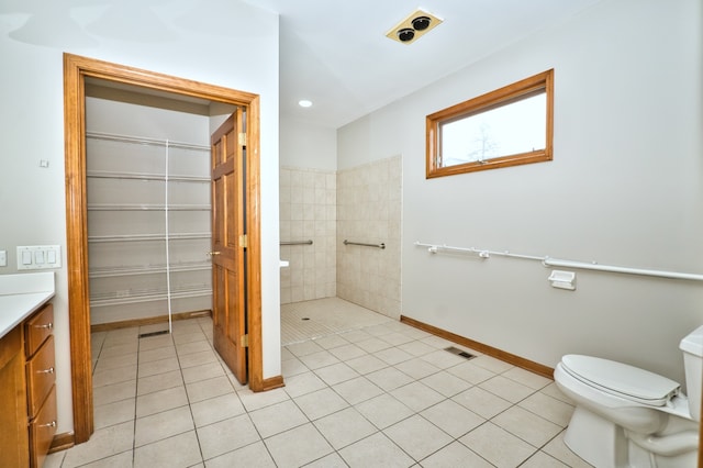 bathroom with a tile shower, vanity, toilet, and tile patterned floors