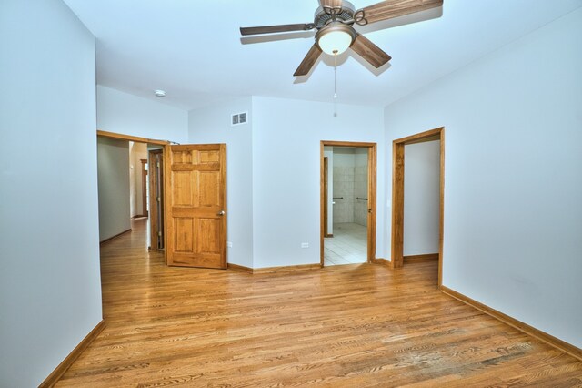 unfurnished bedroom featuring light hardwood / wood-style flooring, connected bathroom, a closet, and ceiling fan