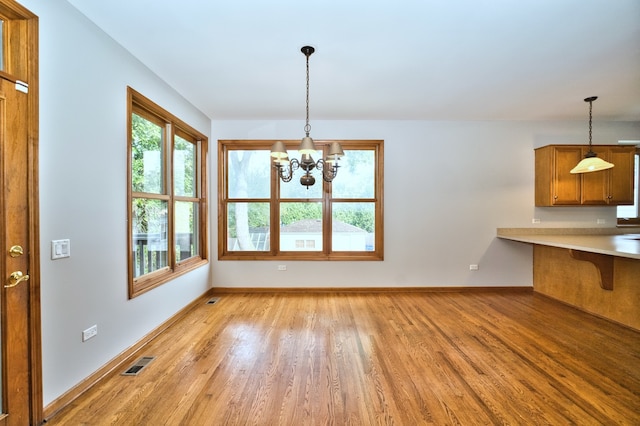 unfurnished dining area with a notable chandelier and light hardwood / wood-style floors