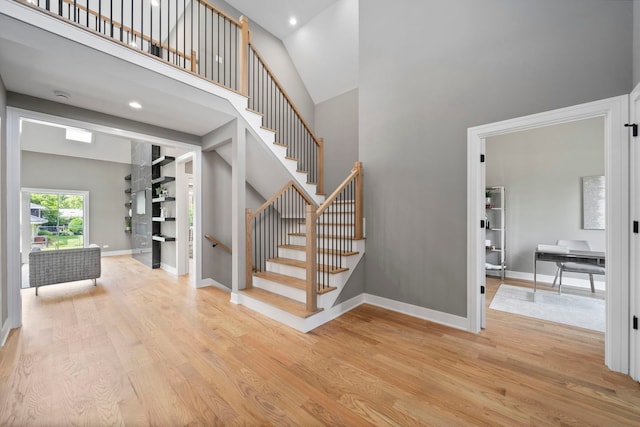 stairs with hardwood / wood-style flooring and high vaulted ceiling