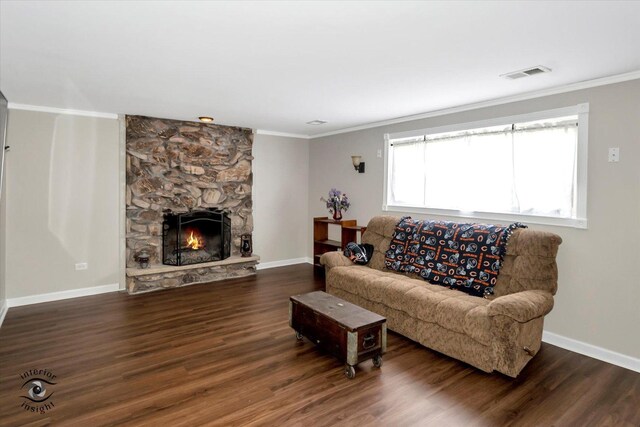 living room featuring dark hardwood / wood-style flooring, crown molding, and a stone fireplace