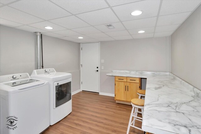 clothes washing area featuring washer and clothes dryer and light hardwood / wood-style flooring