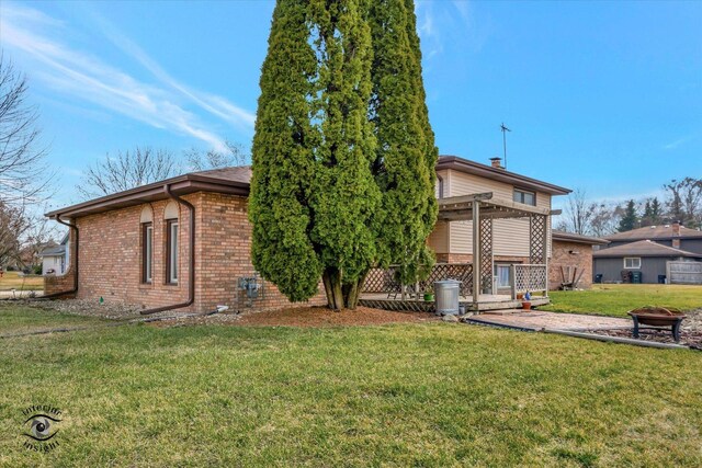 rear view of house with an outdoor fire pit, a yard, and a pergola