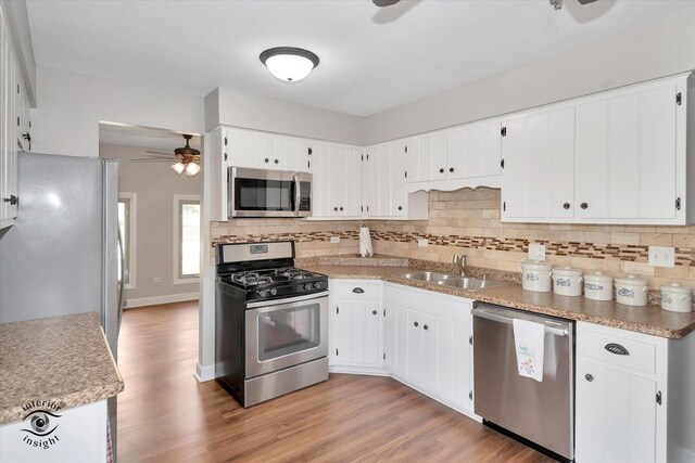 kitchen with sink, hardwood / wood-style floors, white cabinetry, and stainless steel appliances