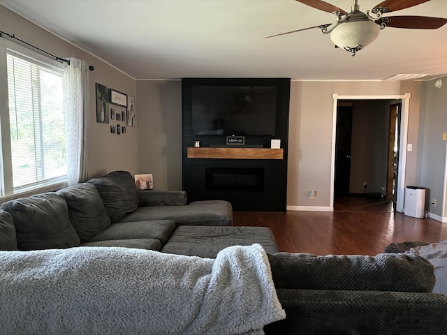 living room featuring dark wood-type flooring, ceiling fan, and a fireplace