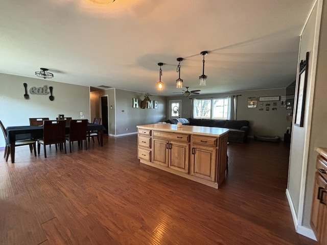 kitchen with hanging light fixtures, a center island, dark wood-type flooring, and ceiling fan