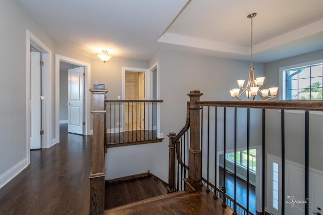 staircase featuring a wealth of natural light, hardwood / wood-style floors, an inviting chandelier, and a tray ceiling