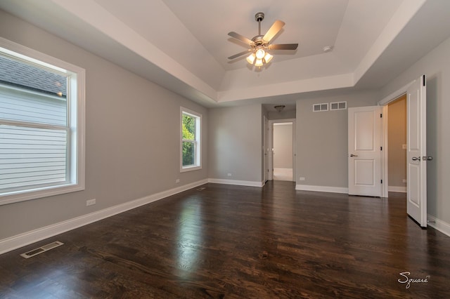 interior space with dark hardwood / wood-style floors, ceiling fan, and a tray ceiling