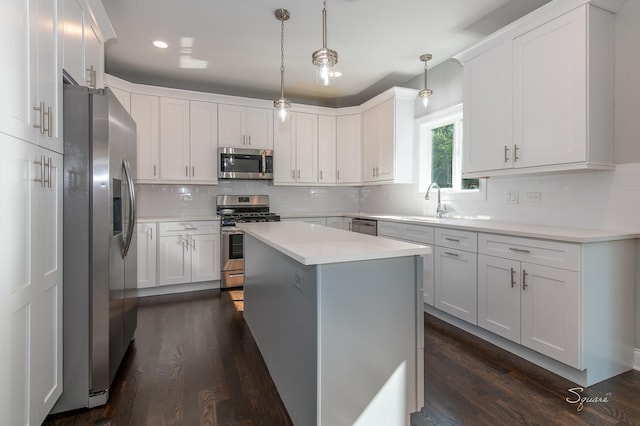 kitchen featuring dark wood-type flooring, decorative light fixtures, a kitchen island, stainless steel appliances, and white cabinets