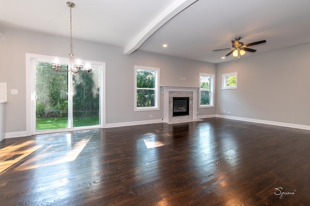 unfurnished living room with beamed ceiling, ceiling fan with notable chandelier, a wealth of natural light, and a high end fireplace