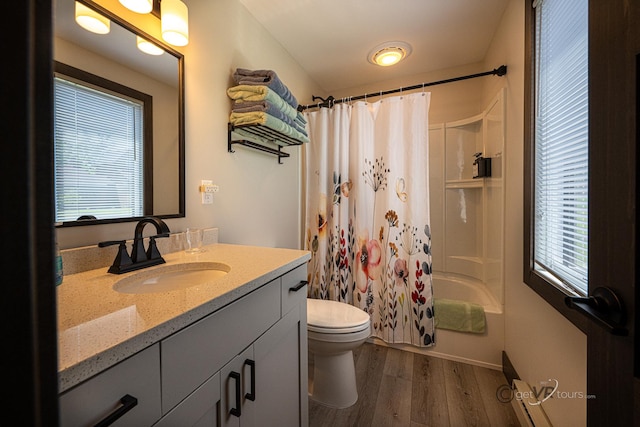 full bathroom with hardwood / wood-style floors, shower / bath combination with curtain, a healthy amount of sunlight, and vanity