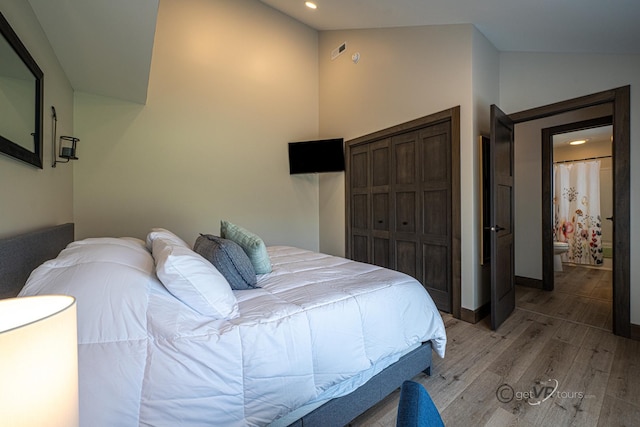 bedroom with light hardwood / wood-style floors, a closet, and lofted ceiling