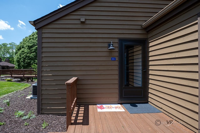 view of exterior entry featuring central AC unit and a deck