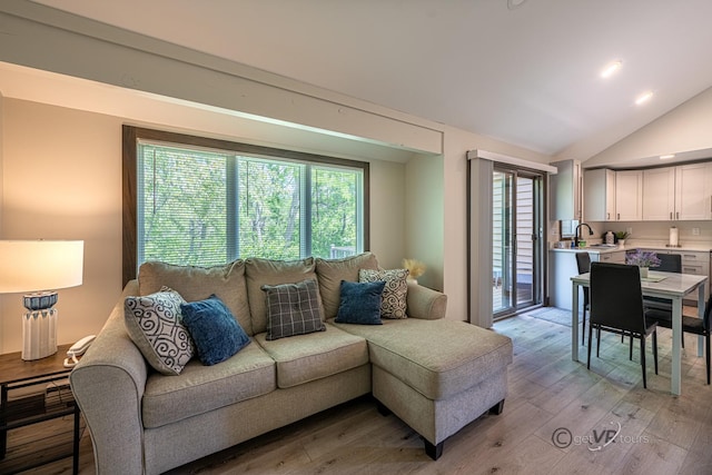 living room featuring light hardwood / wood-style flooring, lofted ceiling, and sink