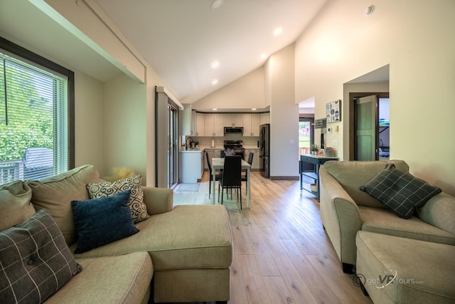 living room featuring high vaulted ceiling and light wood-type flooring