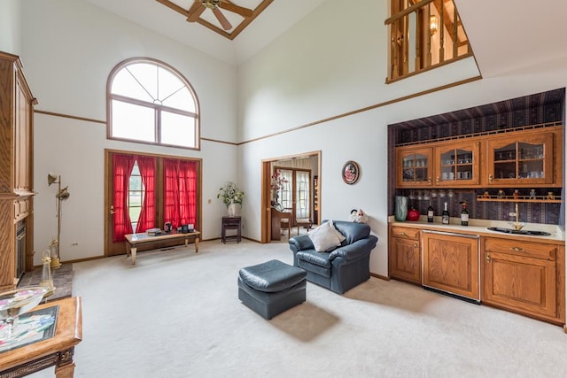 carpeted living room featuring ceiling fan, high vaulted ceiling, and indoor bar