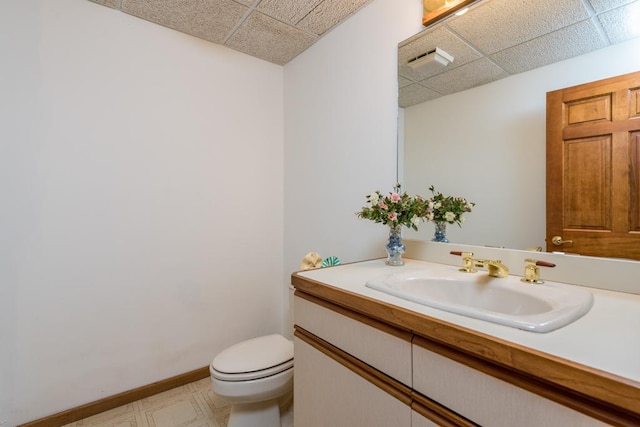 bathroom featuring vanity, toilet, and a drop ceiling