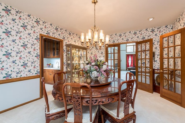 dining space with french doors, light colored carpet, a chandelier, and sink