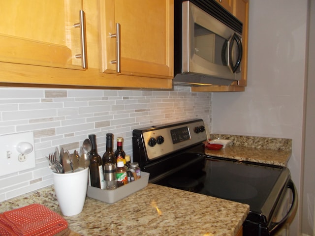 kitchen with appliances with stainless steel finishes, tasteful backsplash, and light stone countertops