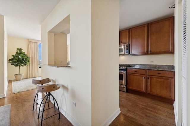 kitchen with a breakfast bar area, stainless steel appliances, and dark hardwood / wood-style floors