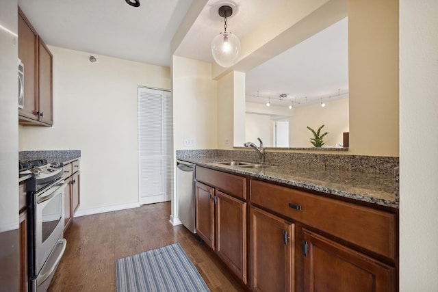 kitchen featuring appliances with stainless steel finishes, pendant lighting, sink, dark stone countertops, and dark wood-type flooring