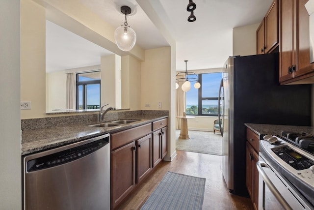 kitchen featuring sink, hanging light fixtures, kitchen peninsula, stainless steel appliances, and light hardwood / wood-style flooring