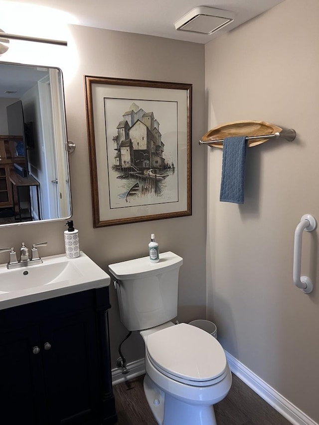 bathroom with baseboards, wood finished floors, toilet, and vanity