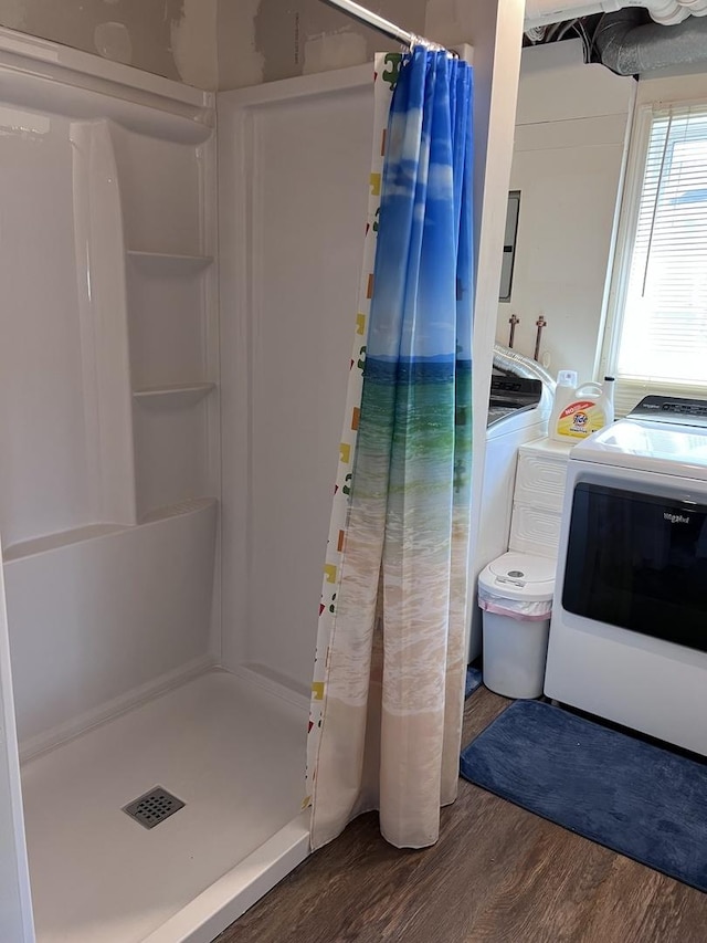 full bathroom with separate washer and dryer, a stall shower, and wood finished floors