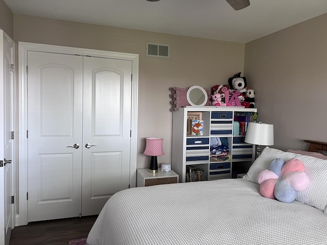 bedroom with dark wood-style flooring, visible vents, and a closet