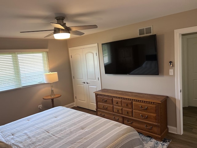 bedroom featuring a ceiling fan, visible vents, dark wood finished floors, baseboards, and a closet