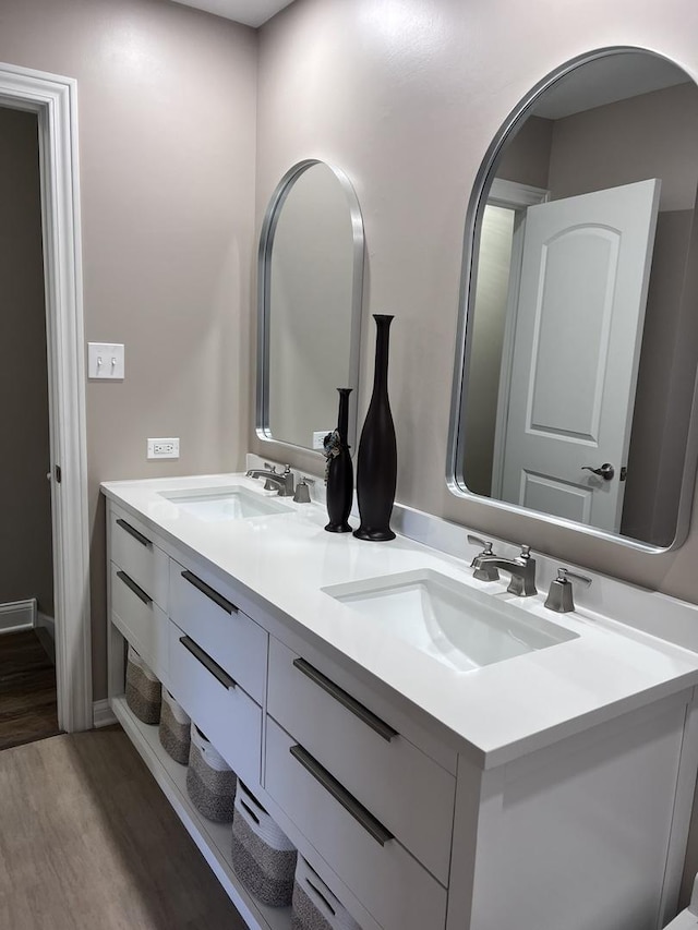 bathroom with double vanity, a sink, and wood finished floors