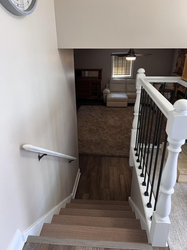 staircase with a ceiling fan and wood finished floors