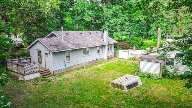 back of house featuring a wooden deck, an outdoor structure, and a lawn