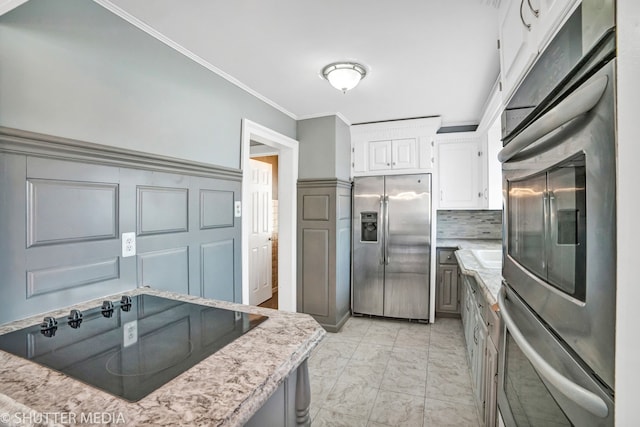 kitchen featuring backsplash, white cabinetry, crown molding, and stainless steel appliances