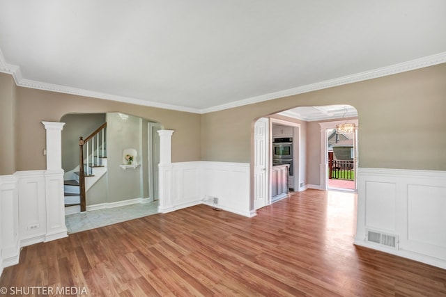 spare room featuring a chandelier, wood-type flooring, and crown molding