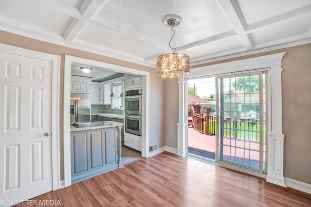 kitchen with hanging light fixtures, tasteful backsplash, white cabinetry, stainless steel appliances, and a chandelier