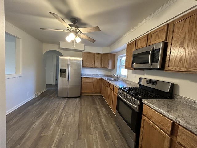 kitchen with dark wood-type flooring, crown molding, sink, ceiling fan, and appliances with stainless steel finishes