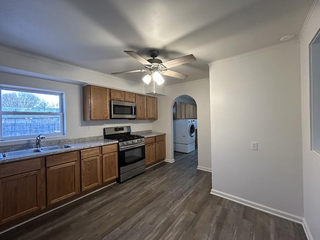 kitchen with washing machine and clothes dryer, ceiling fan, sink, stainless steel appliances, and ornamental molding