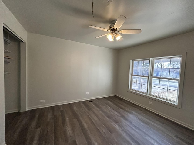 unfurnished bedroom with dark hardwood / wood-style flooring, a closet, and ceiling fan