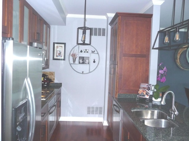 kitchen featuring ornamental molding, dark stone counters, stainless steel appliances, sink, and decorative light fixtures