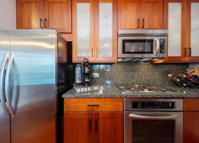 kitchen with backsplash, dark stone countertops, and appliances with stainless steel finishes