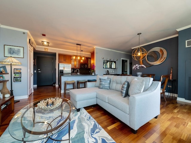 living room with hardwood / wood-style flooring, crown molding, and an inviting chandelier