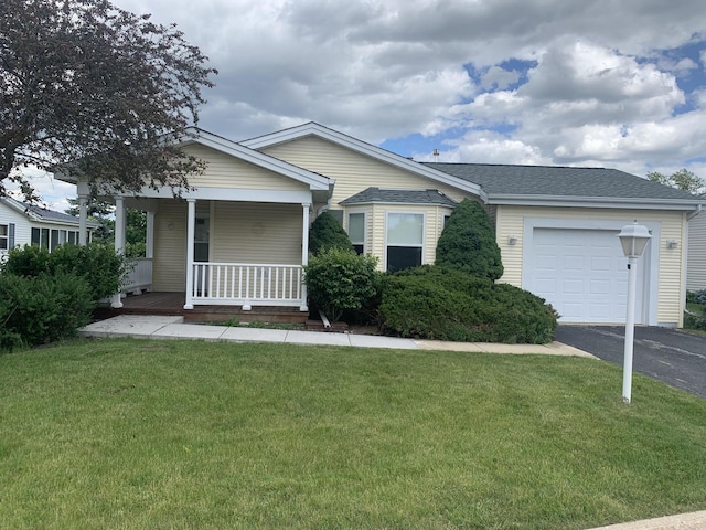 view of front of property featuring covered porch, a garage, and a front yard