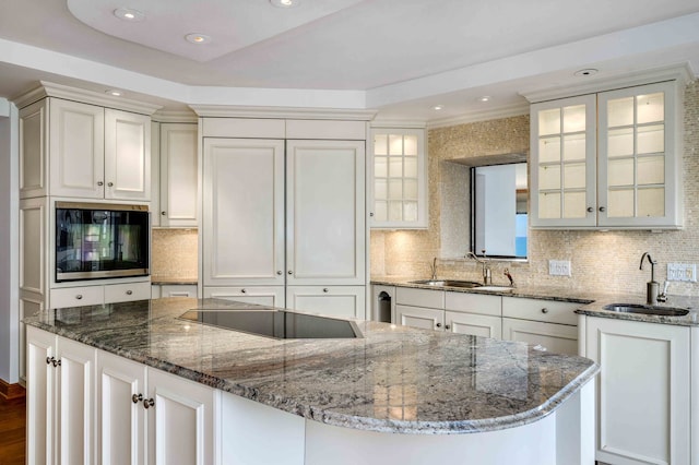 kitchen featuring black electric cooktop, sink, dark stone counters, and white cabinets