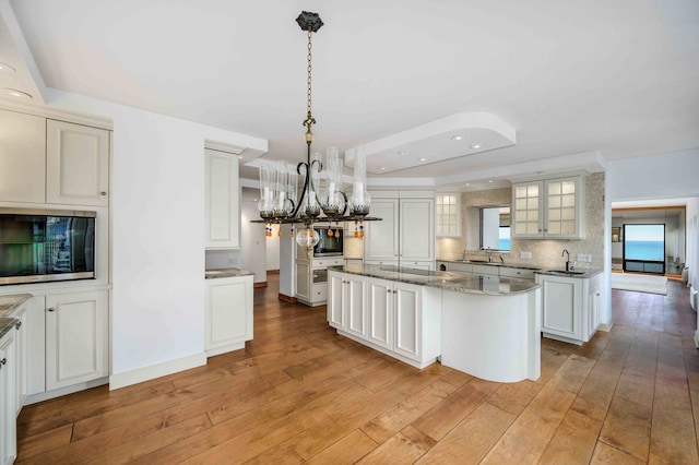 kitchen featuring sink, a center island, stone counters, pendant lighting, and white cabinets