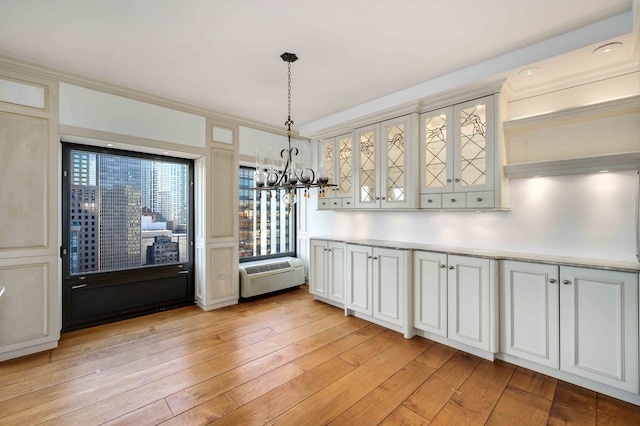 unfurnished dining area with a notable chandelier, light hardwood / wood-style flooring, ornamental molding, and an AC wall unit