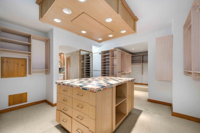 kitchen featuring a kitchen island, butcher block counters, light colored carpet, and light brown cabinetry