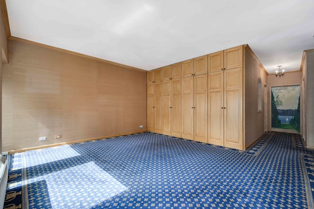 unfurnished bedroom with ornamental molding, carpet, a chandelier, and a closet