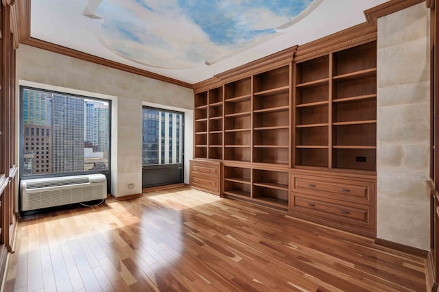 unfurnished room featuring wood-type flooring, ornamental molding, and a wall mounted AC