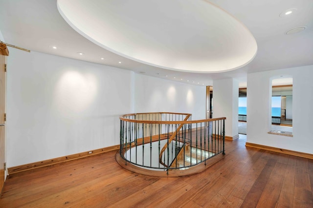 hall with wood-type flooring and a raised ceiling